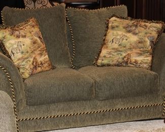 Olive green upholstered love seat with braided accents.