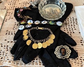 Black gloves 
Charm bracelet 
Enameled bird bracelet 
Ashtray 
Cameo 