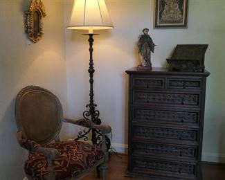 Two icons, carved chest of drawers and book stand, St. Francis, and wrought iron floor lamp create a Spanish Colonial corner.