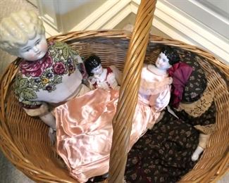 Four china dolls including one large doll with blond hair.