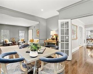 Custom upholstered chairs, square custom table, house plant, marble top sideboard, console