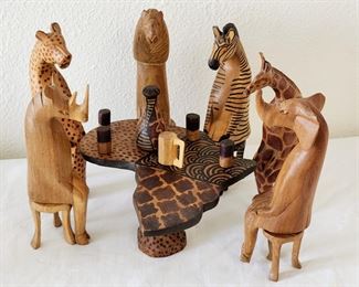 Hand carved wooden African animals sitting on hand carved stools sharing drinks around Africa. A rhino, a cheetah, a lion, a zebra, a giraffe and an elephant walk into a bar...