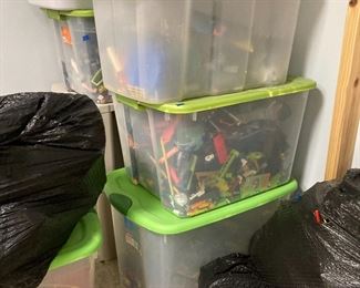 Bins and bags of legos and building sets. The black bags are filled with building pieces