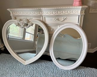 The white heart shaped mirror comes as part of the Disney Cinderella collection. Also, the night stand behind it is part of the Disney collection.