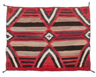 1090
Late 19th/early 20th century; Diné
A Navajo Third Phase Chief-Style Wearing Blanket
Woven in red homespun, cream, grey and dark brown wool with three columns of serrated elements, with striped banding and pictorial elements to corners
43.5" H x 48" W
Estimate: $3,000 - $5,000