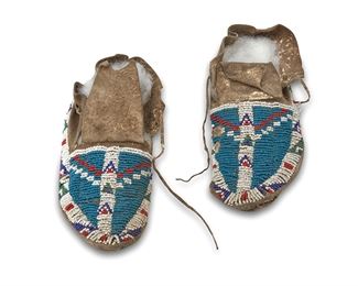 1167
Late 19th/early 20th century
A Pair Of Plains Indian Beaded Moccasins
Each hide moccasin with geometric motifs in blue, white, green and red beads to front and side edges, 2 pieces
Each: 8" L x 2.5" H x 3.25" W
Estimate: $300 - $500