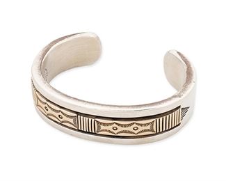 1177
Bruce Morgan (B. 20th Century, Diné)
A Navajo sterling silver and 14k yellow gold cuff bracelet, late 20th/21st century
Stamped: B. Morgan / Sterling / 14K
A heavy silver cuff bracelet set with a central 14k gold stampwork overlay
6.25" total inner C x 0.75" H, with a 1.125" gap
114.1 grams gross
Estimate: $400 - $600