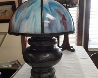 An exquisite kerosene lamp (converted to electric) with a slag glass shade, Stickley lamp with floral shade.  These lamps are located offsite and available for sale June 1-4.