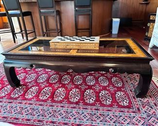 Large Asian inspired glass and wood coffee table.