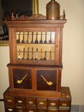 FOLK ART PIPE CABINET WITH PIPES AND INLAID PIPES ON BOTH DOORS.