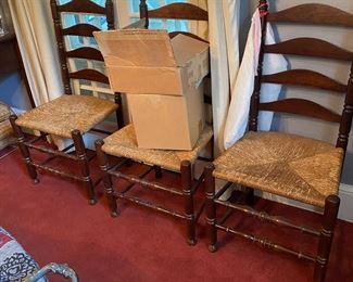 Five ladder back chairs with rushed seats.
