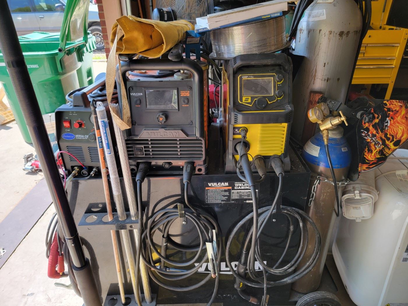 Welding Cabinet with Eastwood Plasma Cutter, Vulcan 205 Welder, ESAB EMP 215ic Welder, Gas Cylinders and various rod/coil supplies.