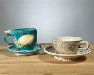 (2PC) ART POTTERY CUP & SAUCERS | Two sets, including a figural bird cup signed Bernadette, and a Strawberry Design cup signed Anna Timlett. -  h. 4.25 x dia. 5 in (bird cup)