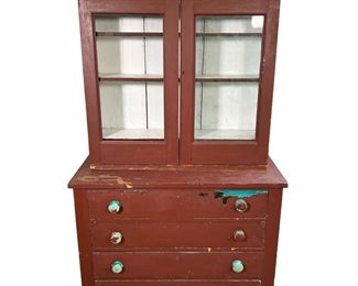 STEPBACK CUPBOARD IN OLD RED PAINT | 19th century Stepback Cupboard in old red paint over blue.  Two glazed doors over 4 Dovetailed Drawers. - l. 41 x w. 17 x h. 68 in