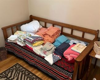 Mission style daybed displaying assorted linens and blankets