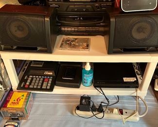 JVC DVD, cassette tape, am/fm stereo,  a vintage electric alarm clock, digital alarm clock and second set of Sanyo speakers