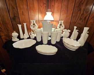 Milk glass collection, vases, platters, grape and vine pitcher and glass set. Milk glass lamp with brass flower pair and taller milk glass and wood lamp in back