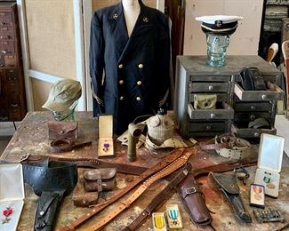 US Military antique to vintage leather weaponry accoutrements, wool Naval uniform jacket & cap, Military Medals, leather holsters and rifle straps, old wooden multi drawer cabinet 
