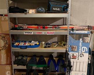Lower Level-Sports Room:  From top to bottom:  coolers; a FISKARS collapsible "turtle" bag;  a SONIC bike helmet; skis (Max-Dynastar and Rossignol); ski poles (Vector-Kerma); a SPORTSCRAFT croquet set; goggles; flippers (SNAP; SPEEDO; HAWAIIAN); ski boots still in their original boxes (NORDICA B-9 and SALOMON); and a pair of rubber boots.  To the right is a new-still-in-the box NSF Chrome rack which has six shelves and measures 48" wide x 18" deep x 72" tall. The 6-shelf rack (48" wide x 18" deep x 84" tall) is also for sale.
