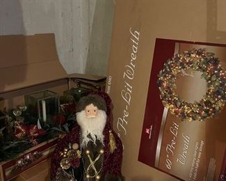 Lower Level-Sports Room:  A "fur" clad Santa is between a  boxed 53" candleholder centerpiece and a boxed  60"pre-lit wreath. 