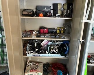 Garage: This storage cabinet displays battery chargers; staple guns; staples; small air compressors; pumps; numerous extension cords.  A set of jumper cables is in the blue bag.  (The cabinet is not for sale.)