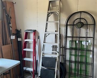 Garage:  Need a ladder?  How tall?  There is a HUSKY 5'; a 9' aluminum ladder; and a COSTCO step ladder.  Also shown left to right are a metal bed frame; a FISKARS trimmer; 2-1/2 ton floor jack; a smaller jack; nine individually priced 80" tall green metal trellises with imbedded glass discs; and bright green metal fence panels.