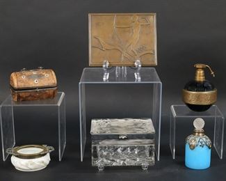         17	Lot of Dresser & Vanity Items	"6 piece lot of dresser and vanity items. Cut crystal box with silverplate mounts, 5""W x 3 3/8""D x 3 1/2""H; Czech amethyst glass Volupte perfume atomizer with gilt nude decoration, 4""H; blue satin glass perfume with enamel decoration, 4""H; Wave Crest pin tray, 4""W; leather and mother-of-pearl box, 3 3/4""L; Lucky Strike cigarette tin with brass art deco Diana The Huntress lid, 5 3/4""W.

Cut crystal box chipped on two sides and at corner, tarnish and losses to patina on silverplate; atomizer missing bulb; sections of enamel missing from satin glass perfume, chips to stopper, losses and corrosion to collar; scratches to Wave Crest and losses to floral decoration; leather box scratches and losses to leather throughout, leather splitting at seams on both sides, rusting to metal, losses to interior; minor losses to patina on Lucky Strike lid, scratches and wear to Lucky Strike box."
