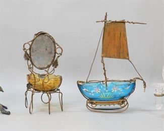         18	4 Dresser & Tabletop Items	"4 piece dresser and tabletop lot. Crystal and gilt metal lyre form epergne, 10""H; enamel decorated glass and gilt metal ship form scent bottle holder with mirror, 11 1/4""H; enamel decorated glass and gilt metal ring dish with mirror, 9 1/4""H; silverplate squirrel form nut dish holder (no dish); 9 7/8""H.

Epergne chips and roughness along base; ship losses to gilt decoration on rim, chips to rim, losses to patina on metal; ring dish losses to gilt decoration on rim, flake to rim, minor losses to patina on metal; squirrel repairs to branch on one side, foot chipped, chip to leaf."
