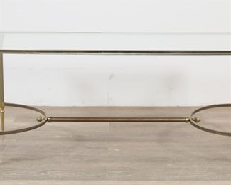         41	Maison Jansen Hollywood Regency Cocktail Table	"Hollywood Regency cocktail table in the style of Maison Jansen. 20th century. Glass top, brass frame and stretcher, reeded legs with Corinthian column capitals. No apparent maker's marks or labels. Tarnishing, blemishes, and wear to brass throughout table. Chips to edge of glass top. Scuffs, scratches and wear throughout glass.

42"" W x 20"" D x 18"" H. 41 lbs."
