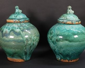         82	Pair of Chinese Pottery Ginger Jars	Pair of Chinese pottery ginger jars / lidded urns. Green crackle glaze, foo dog finials. Each 16 3/4"H. Imperfections to the base of one.
