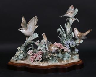        151	Lladro Porcelain Bird Group Spring Birds	Lladro porcelain figure 1368, Spring Birds. Blue Lladro mark to the underside. 11 1/4"L x 8 7/8"H not including wooden base. Chips to purple and white flowers, repair below tallest bird, staining to fabric on base.

