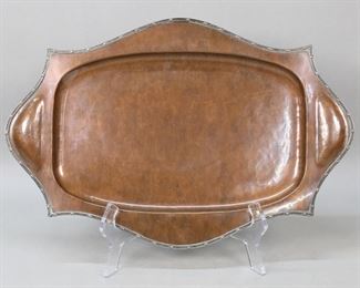        173	A.E. Jones Copper & Silver Tray	Patinated copper tray with silver rim. Unsigned, attributed to A.E. Jones, circa 1910-1920. Impressed on the underside 2503.16"L. Scratches and minor losses to the copper patina, scratches to the underside.
