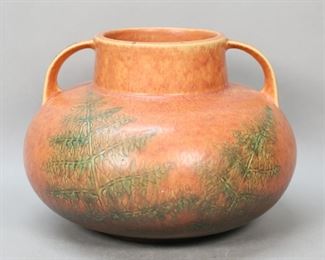        267	2 Handled Art Pottery Vase	Two handled art pottery vase. Brown and green glaze, evergreen tree decoration. Unsigned. 7 1/4"H. Chip to one handle, chips to the base and underside, green paint residue to one handle and paint spots throughout.
