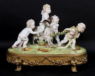        274	Sevres Style Figure Group Cherubs With Goat	Porcelain figure group, putti with goat. Gilt bronze base. Sevres style mark to the underside. 14"L x 11 1/2"H. Chip to the underside.
