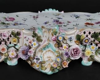        282	Meissen Porcelain Footed Stand	Meissen porcelain footed stand. Scroll feet, hand painted and applied floral decoration. Blue crossed swords mark and incised 535 to the underside. 26"L x 13"D x 4 3/4"H to top of platform. Minor chips to flowers.
