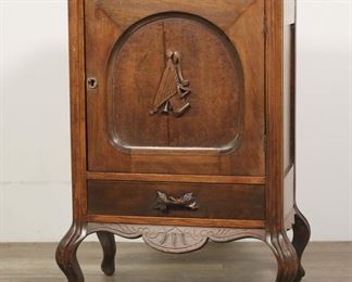        304	Victorian Music Cabinet	"Victorian music cabinet. Oak, one dovetailed drawer, door with carved harp motif. Scratches, stains and wear throughout top of wood. Later plywood shelf in interior. Scratches and nicks to wood of legs. Losses to carved keyhole of door. Small scuffs to wood on face and door of cabinet. Repairs to top of cabinet.

24 1/2"" W x 17 1/2"" D x 34"" H."
