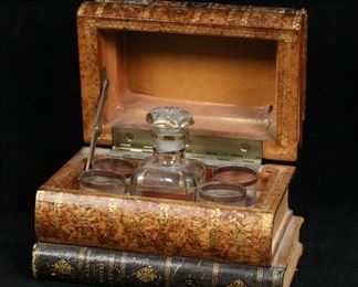        335	French Faux Book Cave A Liqueur Cordial Set	Leather faux book form cave a liqueur or tantalus set. Gilt decorated crystal decanter and 4 cordial / shot glasses. Box stamped Made in France. Book box 7 1/8"W x 4 1/2"D x 5"H, decanter 4 1/2"H. Losses, scratches and fraying to books on corners and edges, losses and scratches to leather on bottom book, losses to gilt decoration on decanter, decanter stopper frozen, interior end of stopper chipped.
