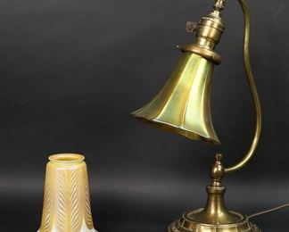        343	Brass Desk Lamp With 2 Quezal Art Glass Shades	Brass desk lamp with 2 signed Quezal art glass shades. Pulled feather and iridescent. Lamp base unsigned. Iridescent shade 5"H, 5 1/2"-diameter (2 1/4"-diameter at top); pulled feather shade 5 1/4"H, 5"-diameter (2 1/8"-diameter at top). Scratches to iridescent shade, minor wear and losses to color at rims of both, minor wear and losses to brass patina on lamp base.
