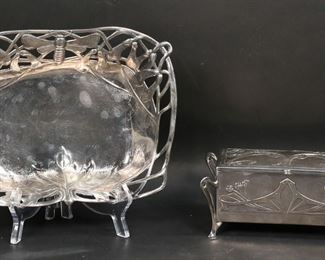       344	WMF Silverplate Box & Walter Scherf Pewter Dish	2 piece art nouveau lot. WMF (Wurttembergische Metallwarenfabrik) box, silverplate, with wood lining and floral decoration, 6 7/8"W x 4 1/2"D x 2 7/8"H; Walter Scherf dish, pewter, openwork rim with insect and leaf decoration, marked on the underside Osiris 609 Isis, 9"L x 7 1/8"W x 1 1/2"H. Splits to wood lining on lid of WMF box, Scherf dish with slight bend and does not sit flat.

