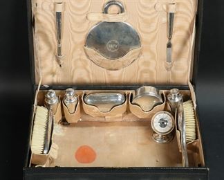       350	Tiffany & Co. Makers Sterling Travel Vanity Set	"12 piece Tiffany & Co. Makers sterling silver travel vanity / dresser set, in leather case. File, button hook, hand mirror, 3 bottles, soap box, canister, box, 2 brushes; with an associated Tiffany Makers travel thermometer. In a fitted leather case. Sterling all stamped Tiffany & Co. Makers Sterling Silver with M mark, circa early / mid-20th century; leather case gilt stamped along front edge Tiffany & Co. Makers New-York, hardware marked England. Sterling all hand hammered and monogrammed, except thermometer. Sterling 1402 grams total, including mirror, brushes, thermometer. Round box 1 1/8""H x 2 7/8""-diameter; leather case 14 1/2""L x 10 3/4""D x 4 1/2""H. 
Set appears incomplete. End of file broken, plastic on thermometer cracked; case with tears, staining, discoloration and losses to lining, wear and losses to leather on corners and edges of case, scratches, losses to fabric cover on handle."
