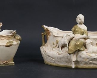        380	Figural Royal Dux Porcelain Planter & Vase	2 pieces Royal Dux porcelain. Planter, woman with lambs, 10"L; vase, boy playing, 7 1/2"H. Both with pink triangle marks. Repairs and roughness to rim of vase and chip to corner of base.
