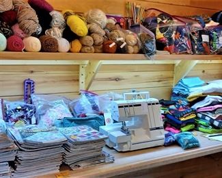The shelf in the back of the craft room, fabric yarn, needles, fat quarters, a Viking Husqvarna Serger 