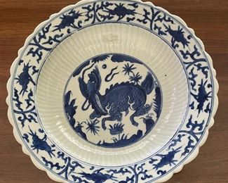 BLUE & WHITE PROVINCIAL MING DYNASTY BOWL WITH BARBED RIM DECORATED WITH PEACHES AND FLUTED CELADON INTERIOR WITH QILIN IN THE CENTER 10 1/2” IN DIAMETER. 
The qilin is a Chinese mythological beast that symbolizes good luck and prosperity. According to tradition in China, a qilin would appear to signal the birth or death of a particularly benevolent ruler or sage scholar.