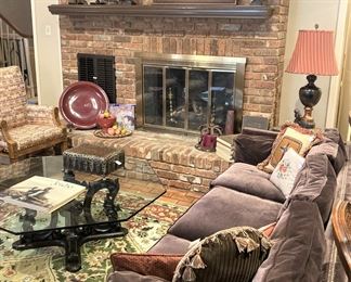 Long brown sofa; glass top coffee table; hearth décor 