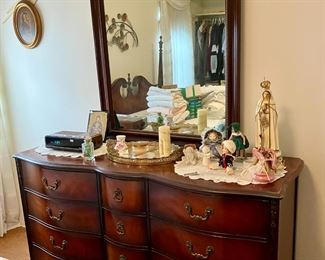 Mirrored dresser, part of a queen bedroom set. Antique dolls and figurines, alarm clock.