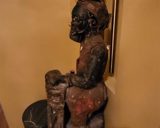 sculpture a carved figure playing percussion instrument with burlap clothes and encrustation.