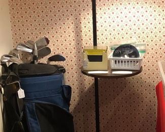 Golf bag and clubs.  Floor lamp with small round shelf on step-on switch on cord.