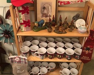 Mugs-Sets of Christmas mugs.  Gnomes. Christmas stocking with the letter "L".  Metal wall art to the left.  Christmas scarf and box and cap.