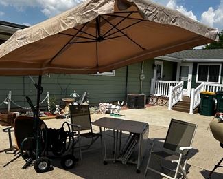 Cantilever hanging patio umbrella, 
with a rectangle patio table w/ w wings underneath the two wings
 wings, (you can see the right wing is down. Left wing is up and underneath the middle section there are two of the four patio chairs in the pic. that go with this table , there are two are folded out. There’s also a cover that covers the table and the chairs. 