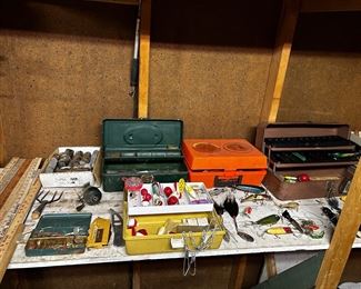 More tacle boxes, lures, accessories 4 point frog/fish spear, fish graffer hanging in the middle, the orange container is an ‘Illuminator 3000’ for emergencies and yard sticks on the left.